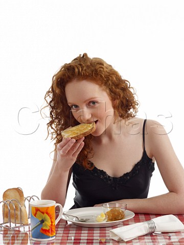 Young woman at breakfast table toast and marmalade mug of tea
