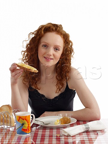 Young woman at breakfast table toast and marmalade mug of tea