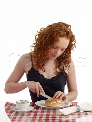 Young woman at breakfast table bagel with ham and cream cheese cup of black coffee
