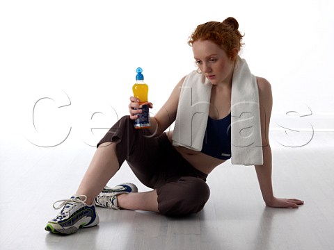 Young woman resting with sports drink after workout in a gym