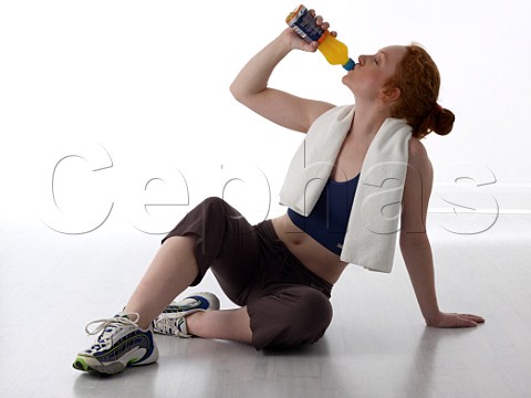Young woman resting with sports drink after workout in a gym
