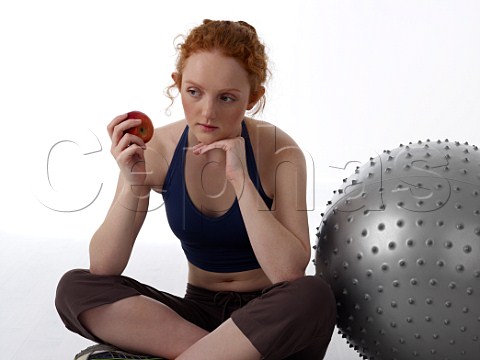 Young woman with apple after workout in a gym