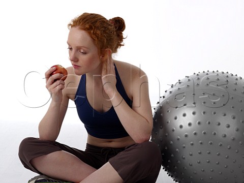 Young woman eating an apple after workout in a gym
