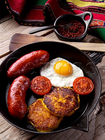 Llapingachos Equadorian cheese and potato patties with fried egg tomato and chorizo sausage in a frying pan