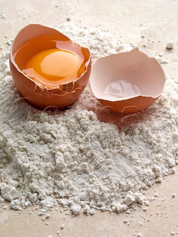 Pile of flour with opened egg in shell