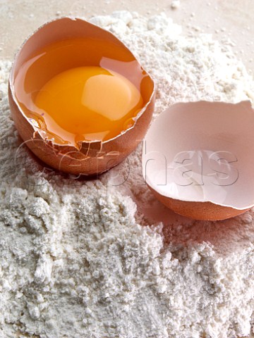 Pile of flour with opened egg in shell