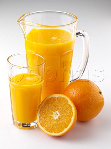 Glass and jug of orange juice with oranges