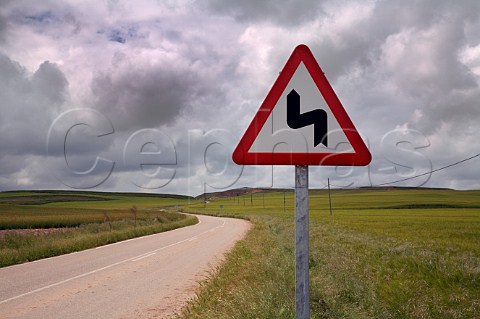 Sign for twisty road amidst the barley fields on the meseta near Castrillo de Duero  Castilla y Len Spain