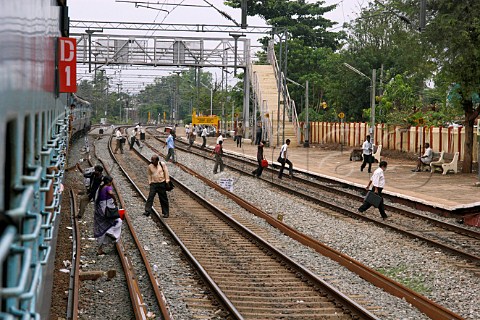 Train passengers cross the tracks at a station between Kochi Cochin and Kannur Cannanore Kerala India
