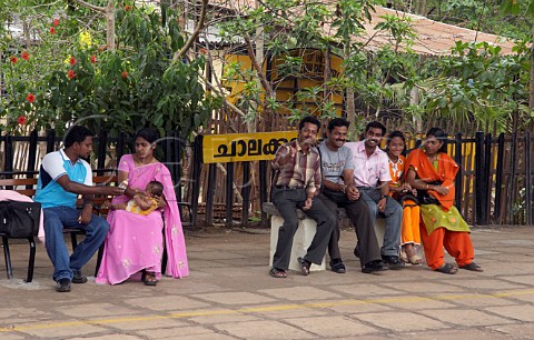 Passengers sitting on the platform of a train station between Kochi Cochin and Kannur Cannanore Kerala India
