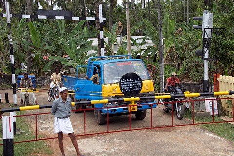 Vehicles and pedestrians waiting at a level crossing near a train station between Kochi Cochin and Kannur Cannanore Kerala India