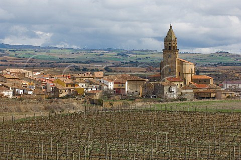 View over vineyard to village of Elvillar with wind turbines on the ridge in distance Alava Spain Rioja Alavesa