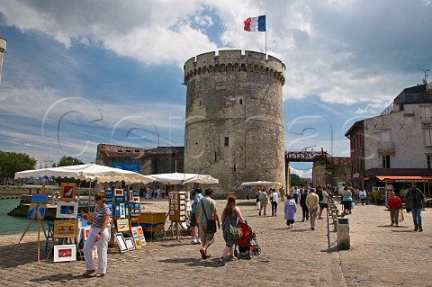 Artists selling pictures to tourists in front of La Chaine tower at the entrance to the ancient harbour at La Rochelle CharenteMaritime France