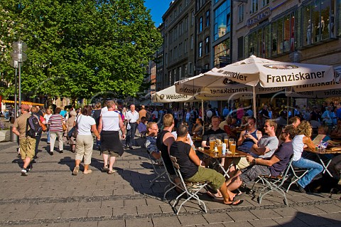 Young men enjoying local draught beers in the sunshine at the Augustiner Bierhalle near Marienplatz Munich Bavaria Germany