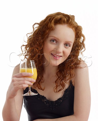 Young woman at breakfast table with glass of orange juice