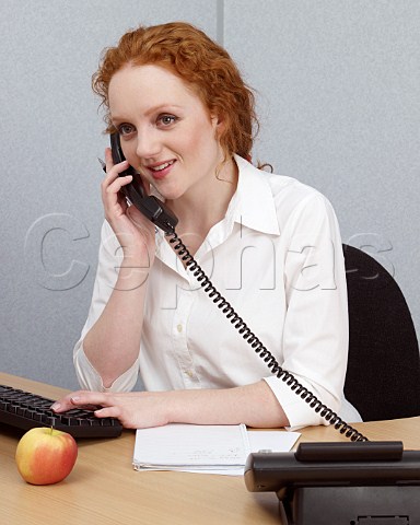 Young woman at her office desk talking on telephone
