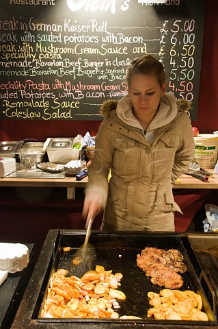 Cooking pork steaks on a food stall at the German Christmas market in KingstonuponThames Surrey England