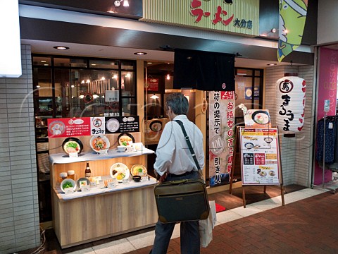 Man looking at plastic food display outside a Ramen noodle restaurant in Oita station Japan