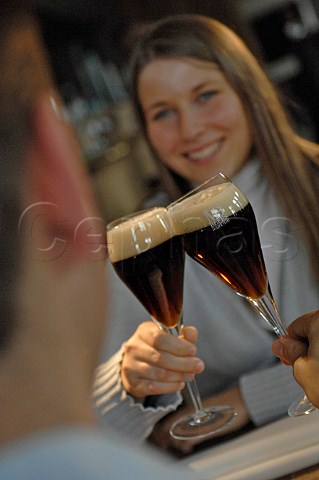 Couple chinking glasses of dark Belgian beer