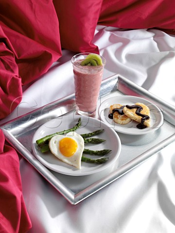 Romantic breakfast in bed heart shaped pancake and fried egg with asparagus spears
