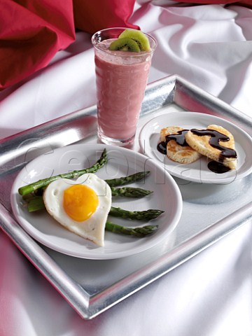 Romantic breakfast in bed heart shaped pancakes and fried egg with asparagus spears