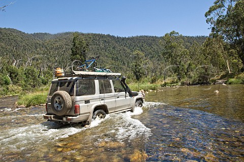 Four wheel drive car crossing Swampy Plains Creek Geehi Valley Kosciuszko National Park New South Wales Australia