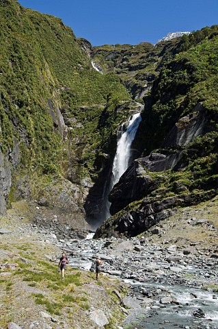 Hikers at waterfall in West Matukituki Valley Mt Aspiring National Park South Island New Zealand