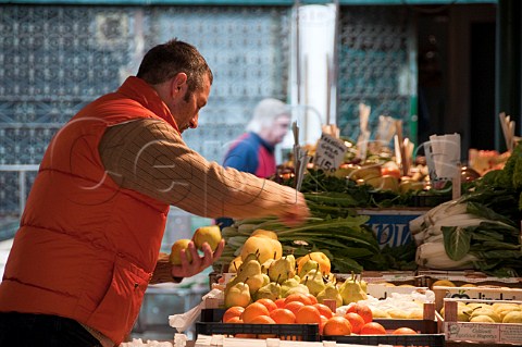 Stall owner setting out pears at the start of the days market Rialto market San Polo Venice Italy