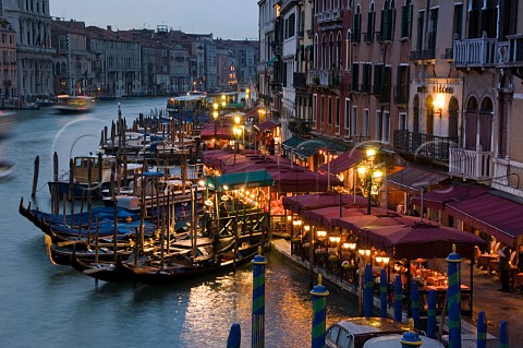 Restaurant seating and gondola moorings on the Grand Canal at night Riva del Vin Venice Italy