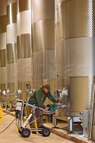 Worker stirring the lees during fermentation in 6000 gallon stainless steel tanks at King Estate Winery  Eugene Oregon USA  Willamette Valley