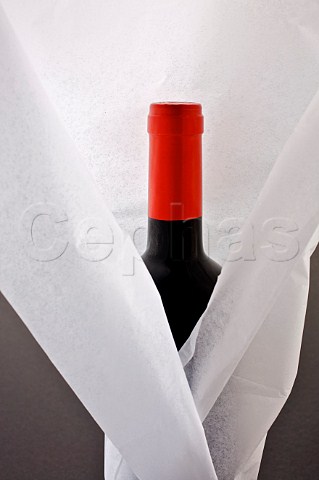 Bottle of red wine wrapped in white tissue paper