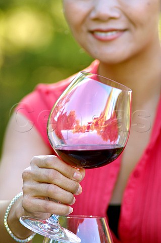 Oriental woman drinking red wine in a vineyard