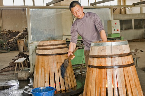 Worker cooling outside of a new barrel with wet brush at Bodega Langes winery near Chang li Chang Li Hebei Province China