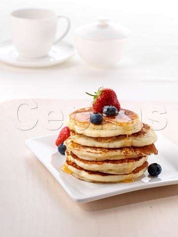 A pile of American pancakes with fruit and honey