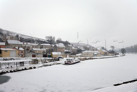 Snow falling on the frozen Canal Latral de la Marne at MareuilsurAy with the Clos des Goisses vineyard of Philipponnat on the hill beyond  Marne France Champagne