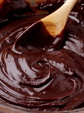Chocolate ganache in a bowl with a wooden spoon