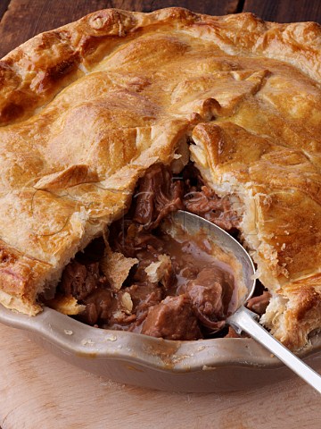 Large steak and kidney pie open with a spoon