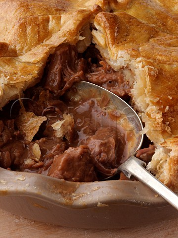 Large steak and kidney pie open with a spoon