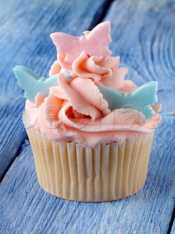 Pink iced cupcake on blue background