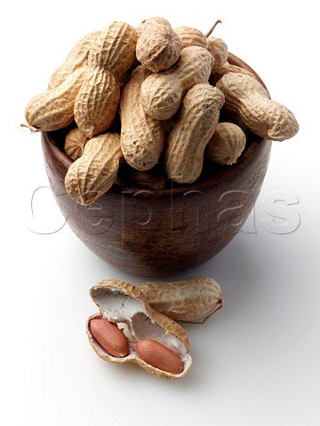 A wooden bowl of peanuts on a white background