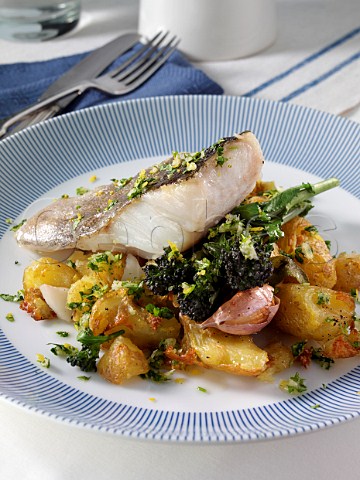 A baked fillet of pollack on a bed of crispy crushed Charlotte potatoes with purple sprouting broccoli sage and garlic and gremolata sauce