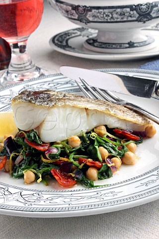 A baked fillet of pollock on a bed of garbanzo beans and spinach