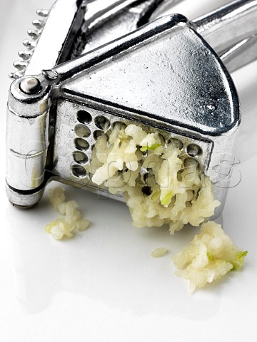Close up of a garlic press with garlic squeezing out
