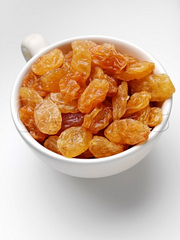 Cup of golden raisins in a cup on a white background