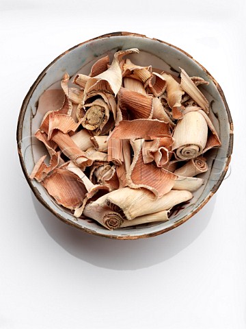 A bowl of dried lemongrass on a white background