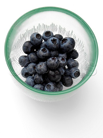 Ripe blueberries in a glass bowl on a white background