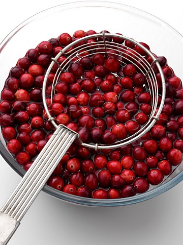 Cranberries in a bowl with a metal strainer