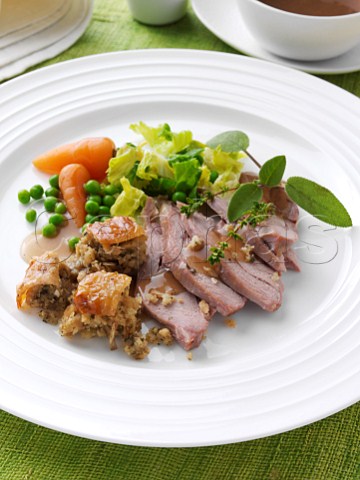 Slices of turkey thigh with peas carrots and stuffing