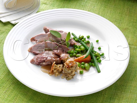 Slices of turkey thigh with peas green beans carrot and stuffing