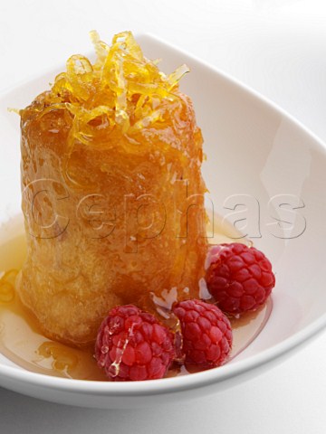 Individual rum baba with syrup and raspberries